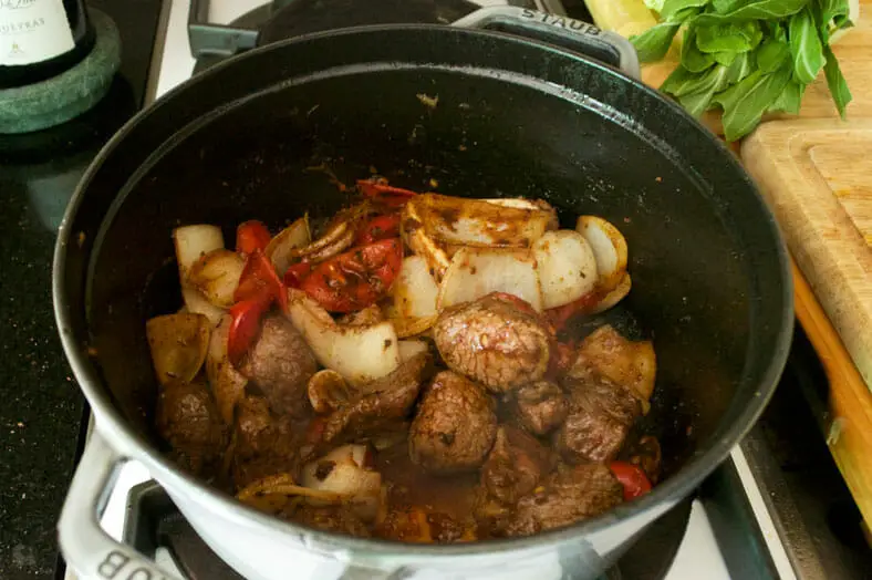 Cooking onions, beef, tomatoes and other ingredients in pan