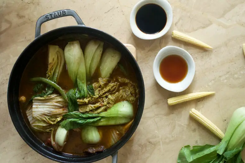 Pork Stew with baby corn, bok choy, cabbage leaves in a pan and sauces