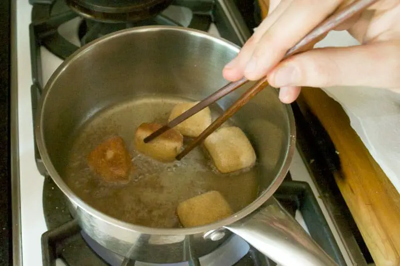 Frying and flipping fresh dough in coconut oil