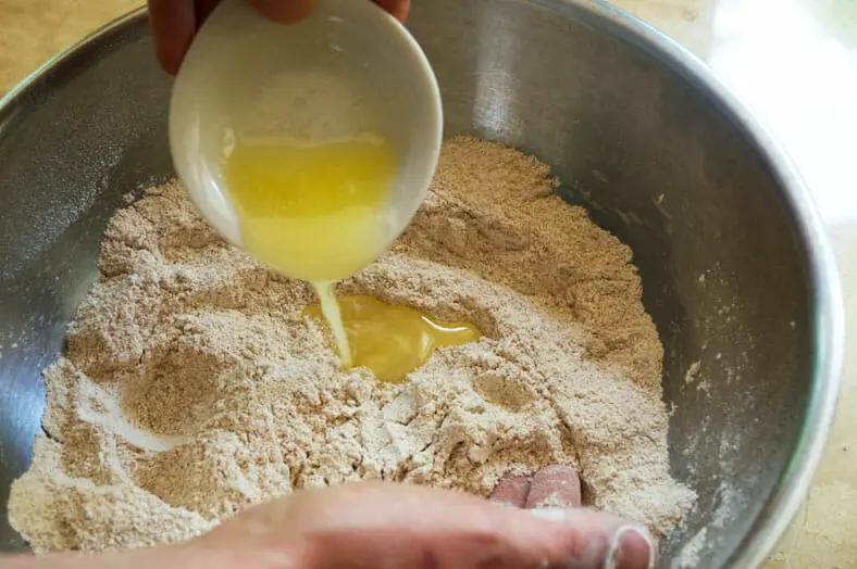Adding melted butter to whole wheat pastry flour, cinnamon, coconut sugar, cardamom, and salt