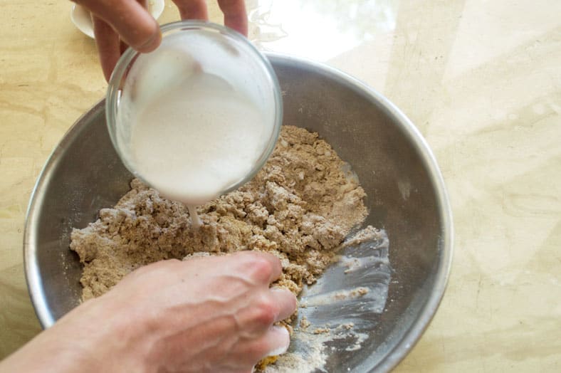 Adding coconut milk to whole wheat pastry flour, cinnamon, coconut sugar, cardamom, and salt to make Kenyan Cardamom Beignets or Doughnut