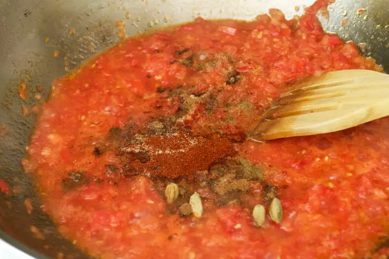 Adding spices to the simmering tomatoes