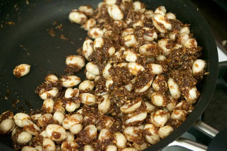 Finishing off the melted coconut sugar, peanuts, coconut flakes in a hot pan to finish Tanzanian Coconut Peanut Brittle