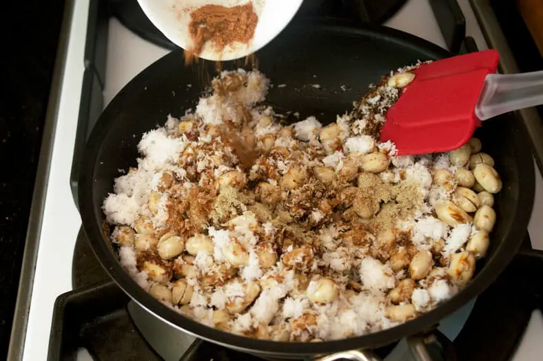 Here we are adding spices to the melted coconut sugar and toasted peanuts for Tanzanian Coconut Peanut Brittle