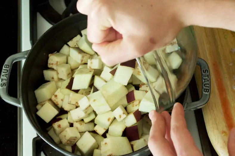 Start by taking a stockpot or Dutch oven over medium-high heat and add your olive oil. Then pour in your cubed and diced eggplant, ensuring that each piece gets nicely coated in oil