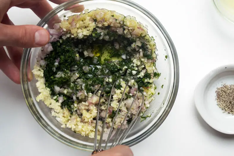 To make chimichurri, an Argentine sauce or marinade traditionally used on grilled meats, you'll need parsley, garlic, vinegar, olive oil and crushed red peppers at a minimum. Simply add the minced parsley, garlic, shallots, olive oil into a bowl and mix with a whisk or spatula.