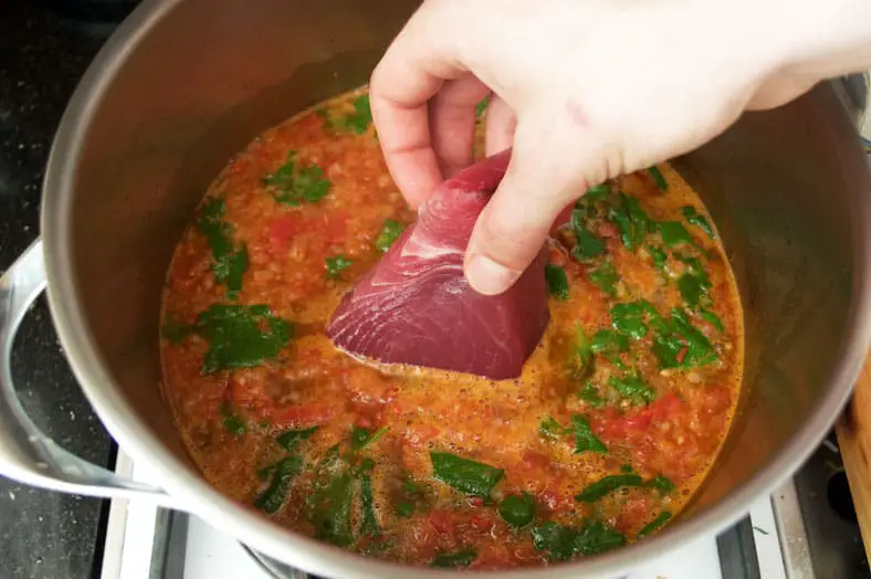 Placing tuna in the soup for stew