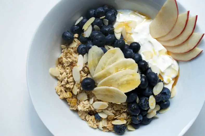 Oats dish with apples, bananas, blueberries, yogurt, honey and sliced almonds