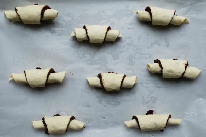 8 mini croissants on a parchment paper before going into the oven. they are rolled into mini crescent shapes