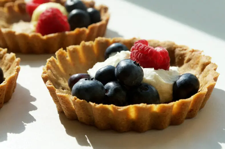 Delicious baked cookies with coconut cream and fresh berries as toppings