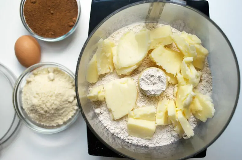 To make the dough for Norwegian Sandkaker, a Christmastime almond buttery wafer like cookie, you start by pulsing together your butter and pastry flour.