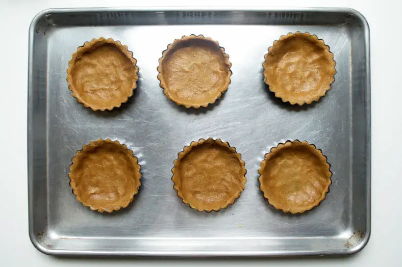 Filled tart tins on a sheet pan and place in the oven to back for 10-15 minutes.