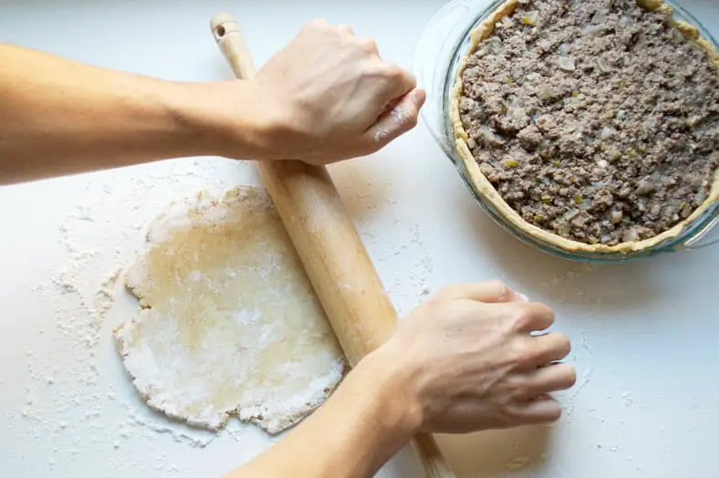 Rolling top crust to cover the filling of pie