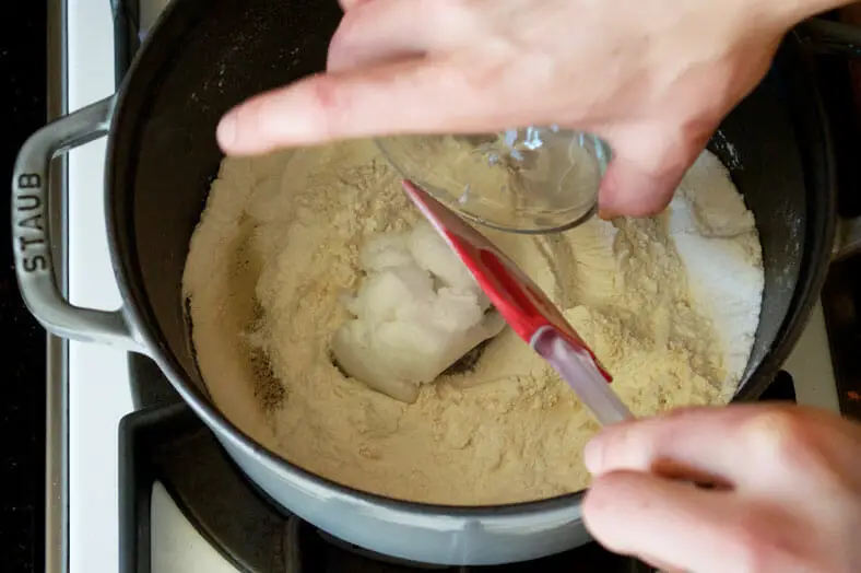 Adding coconut oil to the roasted flour in pan