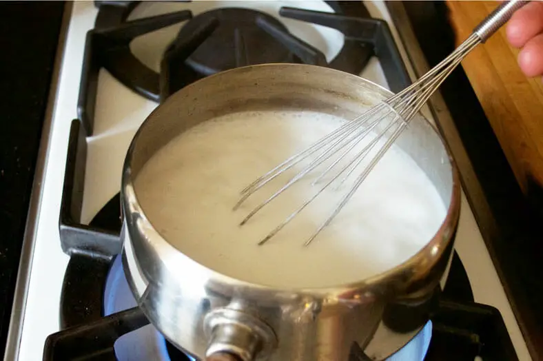 Boiling coconut milk to reduce it down to condensed coconut milk.