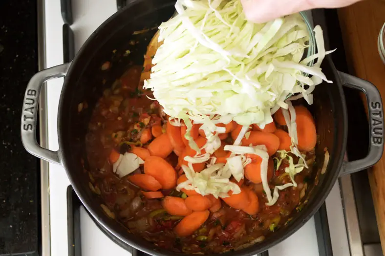 Adding in shredded cabbage and carrots to pot