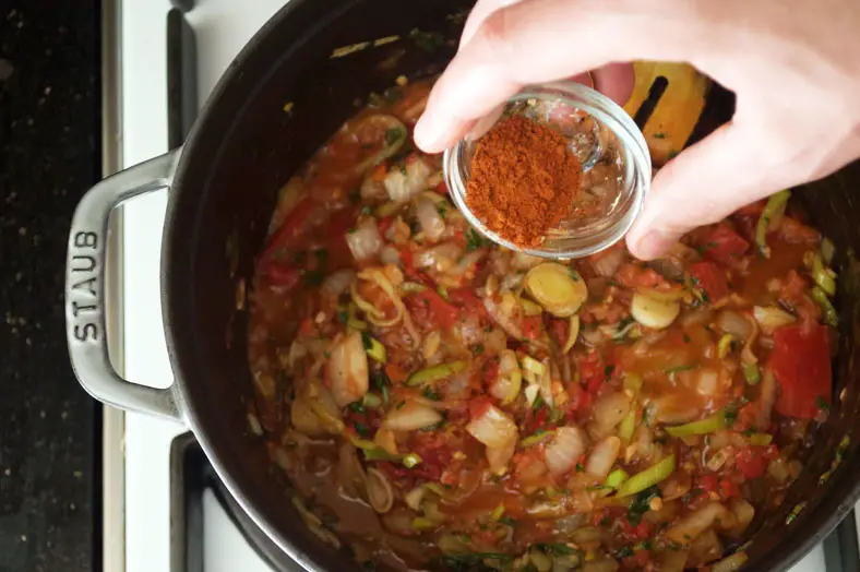 Using plenty of spices - both to color the dish and to add extra flavors. Here you see berbere spice being added to the stew