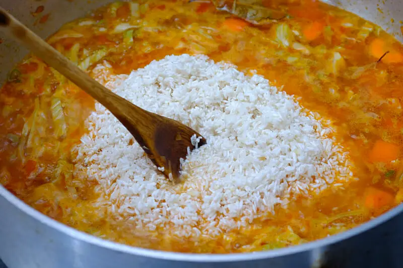 Adding rice to the vegetable in pan
