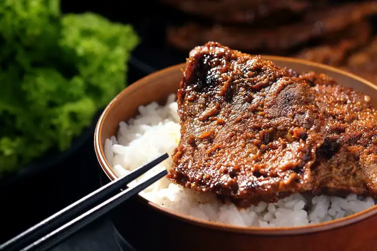 Hot beef placed on the rice with chopsticks