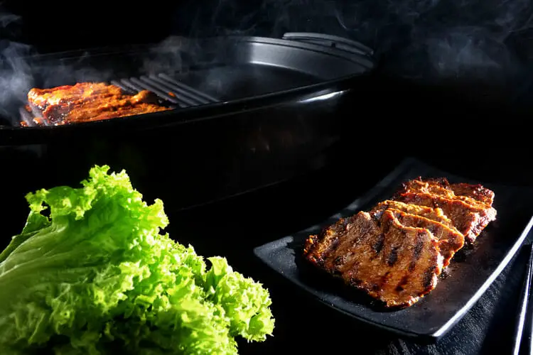 Cooked beef on serving plate with lettuce leaves