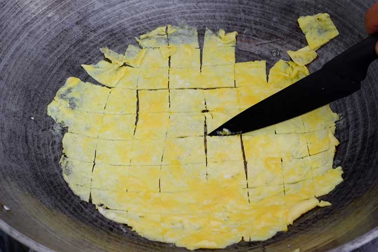 Frying beaten eggs in pan with salt and cutting into square pieces