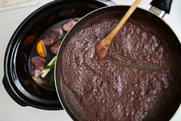 Adding black puree and onion mixture to slow cooker pot