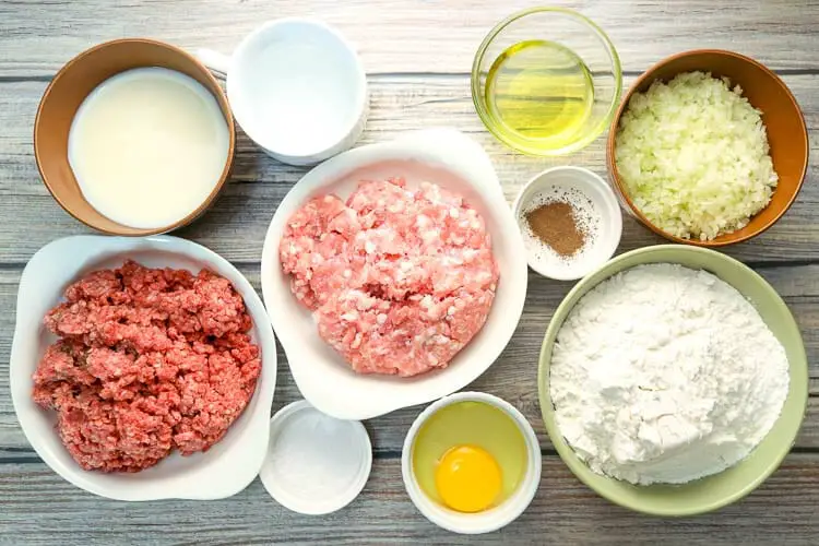 View of ingredients - ground beef, egg, flour, milk, ground pork, garlic, olive oil, salt, black pepper