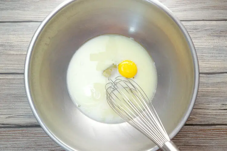 Whisking egg with milk, water, oil and salt in large ball