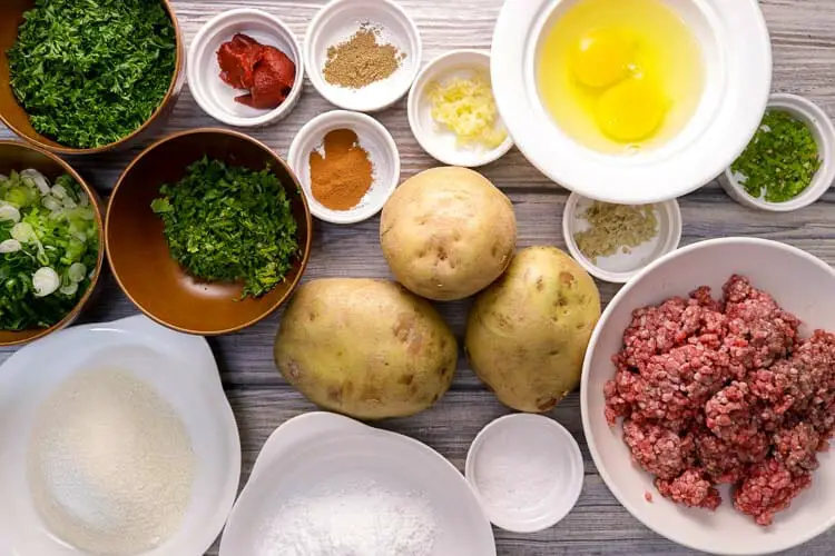 View of ingredients - potatoes, pork, eggs, spices, scallions, ginger, garlic, tomato paste, chillies, breadcrumbs, herbs