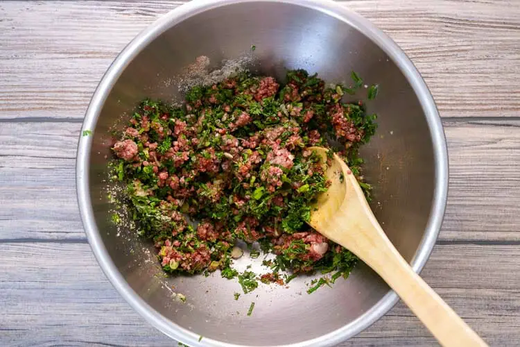 Mixing ground meat with scallions, garlic, ginger, dry spices, chillies, herbs, breadcrumbs and tomato paste for fillings