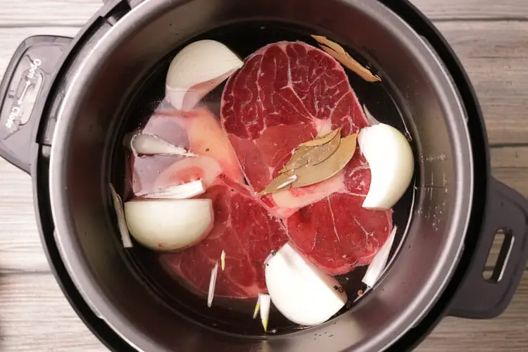 Cook meat with big onion chunks and bay leaves in water in pot