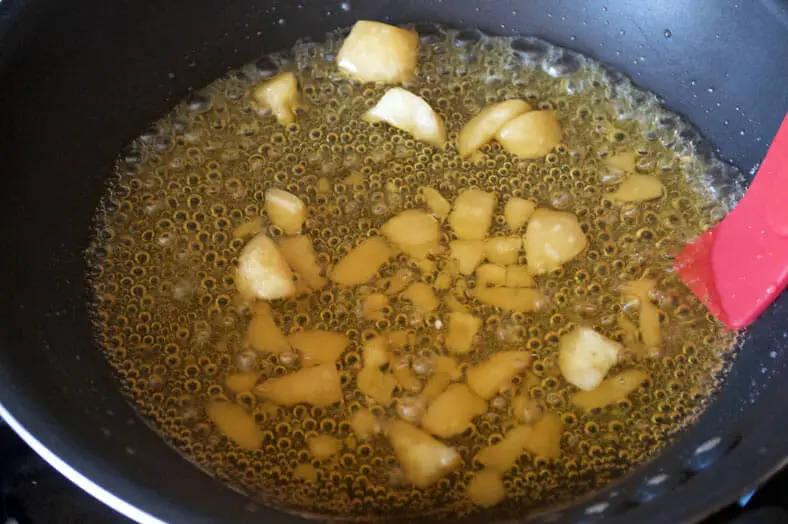 Dissolving of jaggery pieces in water in pan