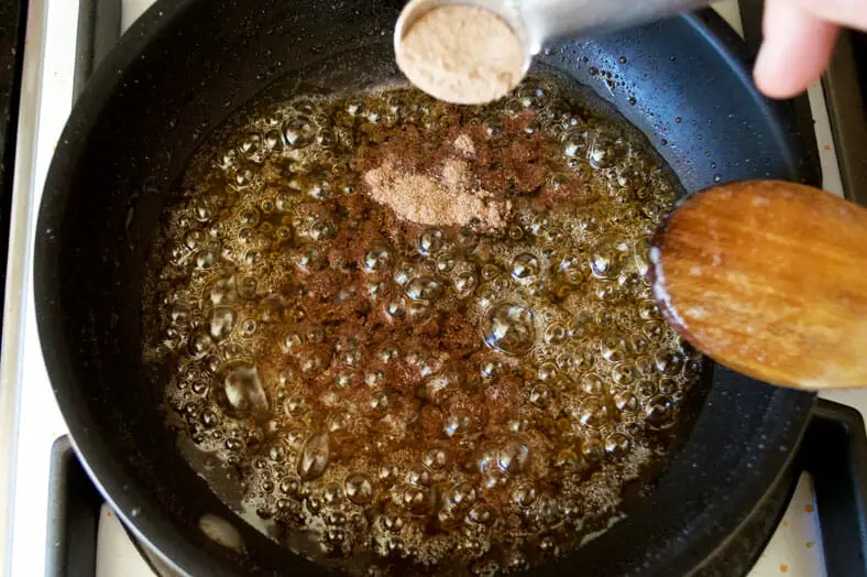 Adding cinnamon powder to jaggery syrup