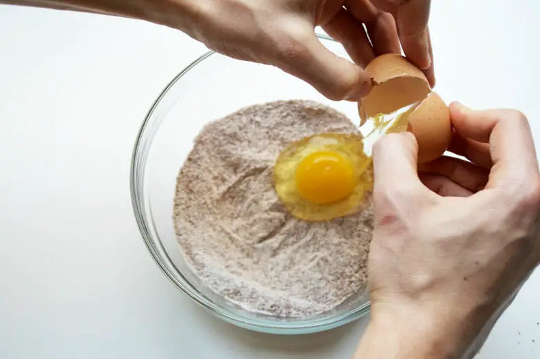 Adding eggs to the flour mixture