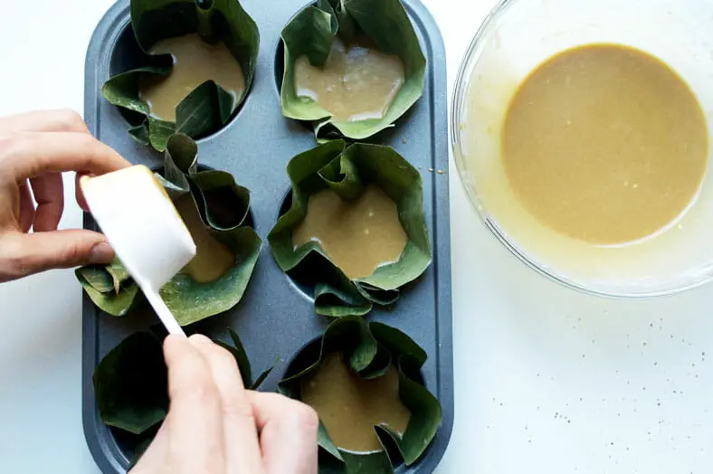 Filling banana leaves halfway with the batter