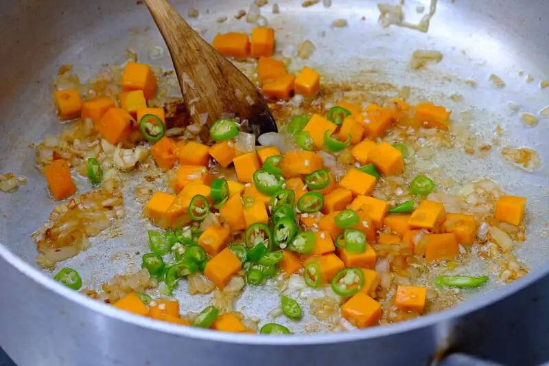 Sautéing chilies, carrots, cabbage in a pan 