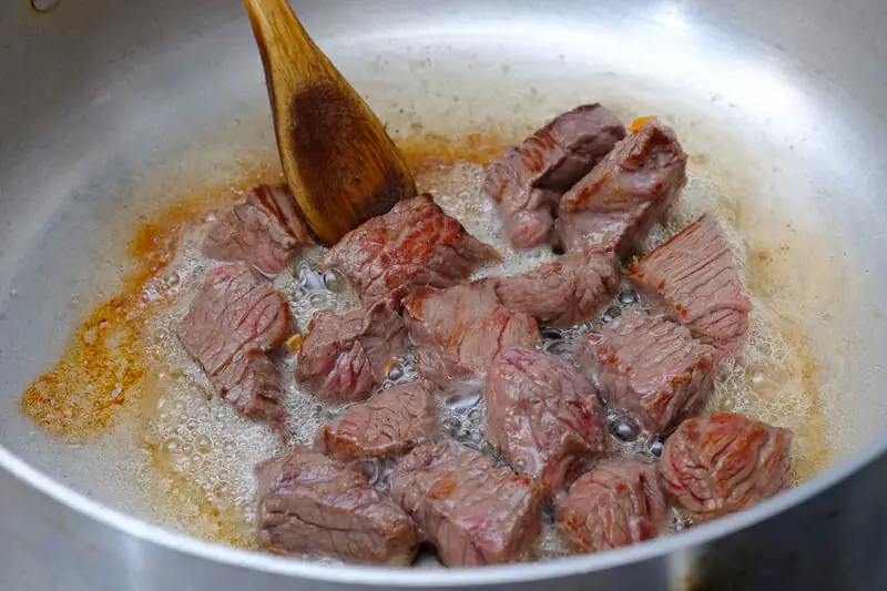 Searing the seasoned meat in pan till brown