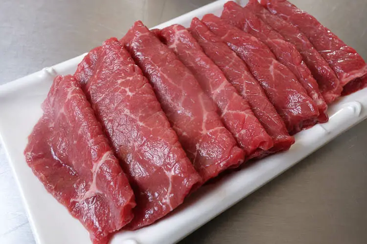 Sliced raw beef on plate on table