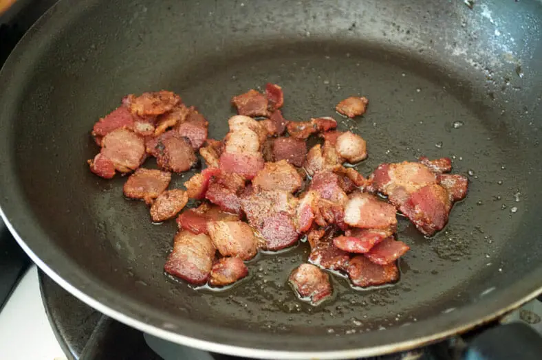 Fully cooked bacon pieces in a pan