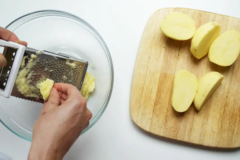 Grating washed and peeled potatoes