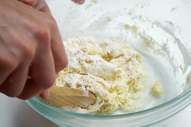 Mixing flour and potatoes with wooden spoon