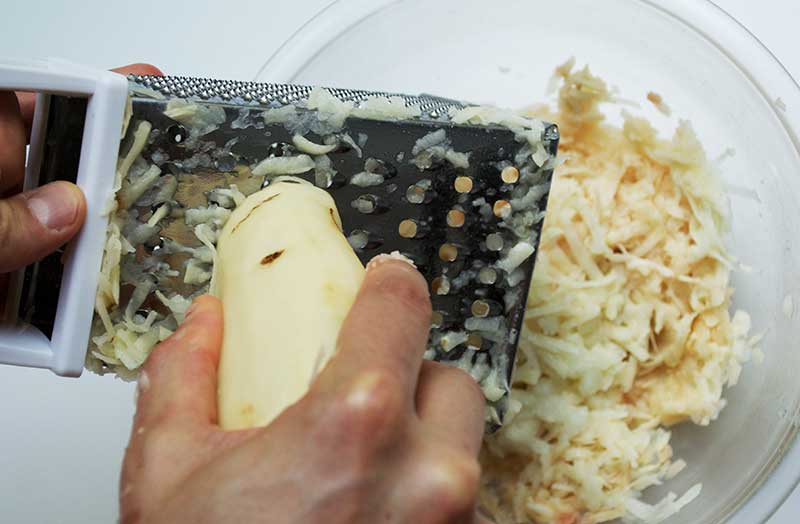 Grating of potatoes into large bowl