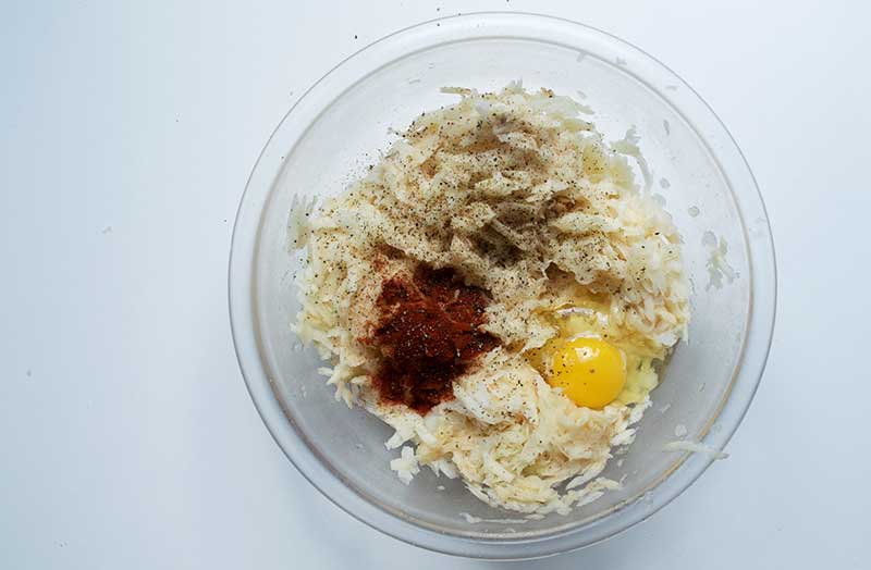 Adding eggs, paprika, salt, pepper to grated potatoes