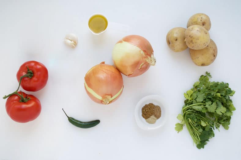 View of ingredients for vegetable stew - onions, potatoes, tomatoes, chili pepper, spices