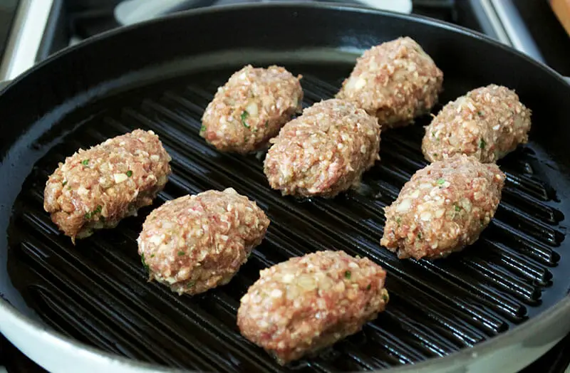Placing meat balls into the grill pan for cooking