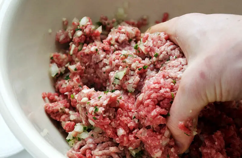 Kneading and squishing of meat with hands for proper mixture