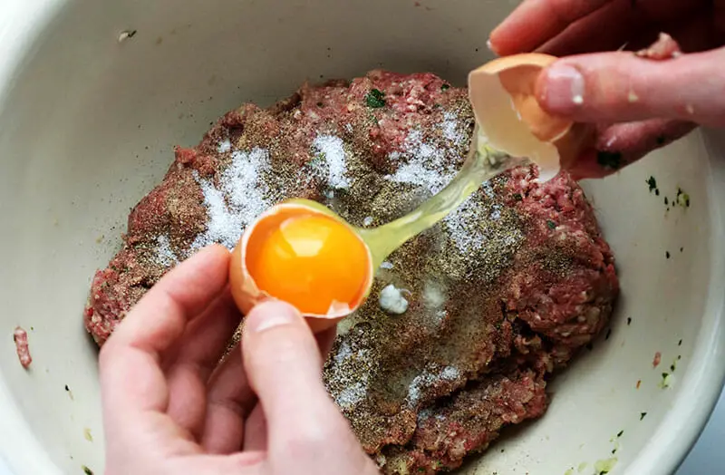 Adding spices and eggs to the kneaded meat