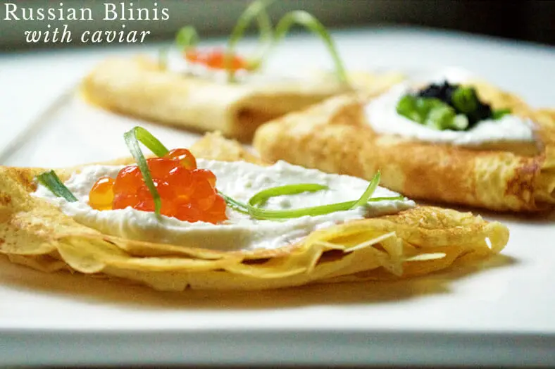 Russian crepe (blini) on a place topped with chives and salmon roe