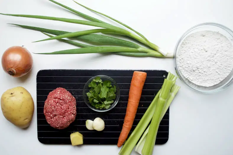 View of ingredients - carrots, flour, meat, garlic, ginger, potato, onion, celery