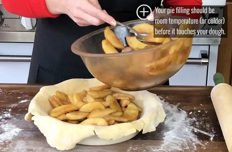 Spoonful of apple fillings on top of bottom dough into plate
